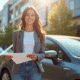 Jeune femme confiante avec sa voiture en ville et documents d'assurance